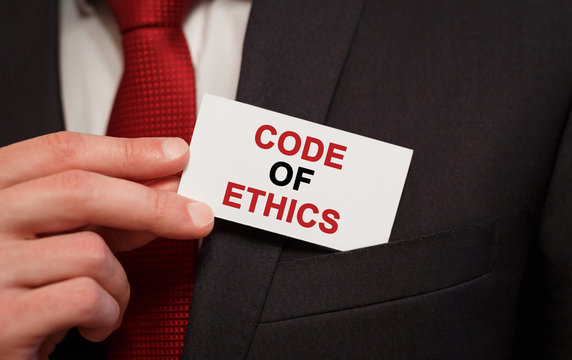 Businessman putting a card with text Code of Ethics in the pocket