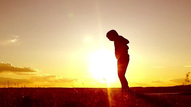 Silhouette of man exercising thai boxing. Silhouette of martial arts man training boxing on the beach over beautiful sunset background. Training karate or boxing on grass field at sunset.