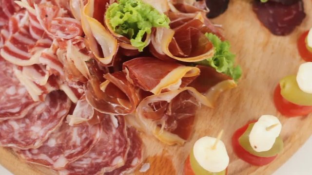 Assorted deli meats, ham, salami, bacon on the wood tray