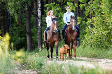 Young happy couple enjoying horse ride in a summer forest.  - 145980897