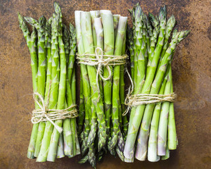 Fresh and raw green asparagus bunches on a vintage background.