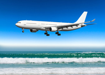 Large plane approaches the landing at the airport low over a tropical beach