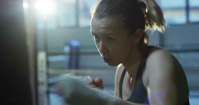 A professional boxer girl in the gym works with a punching bag, a technique of striking, a rack, protection and endurance, erasable bandage. The concept: love of sport, young boxers, love of victory.