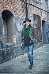 Fototapeta na wymiar Fashionable 30-something woman walking in urban alley