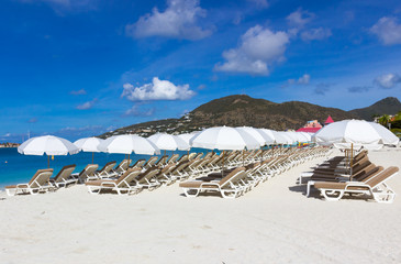  beach chairs and  white umbrellas on caribbean island