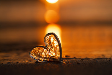 clear glass heart on  sand beach with sunrise sun light - 145988892