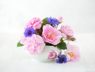 Fototapeta na wymiar Colorful bouquet of light pink roses and cornflowers on pale grey background.