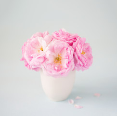 Small  light pink bouquet of roses   in сeramic vase against  of  pale  grey  background.  Shallow depth of field. Selective focus