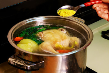 Big chicken is cooked in a saucepan on a gas stove.