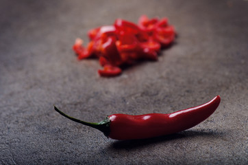 Chopped red chilli pepper on a black background. Spicy on a wooden spoon. Vegetable. Concept of hot...