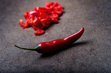 Chopped red chilli pepper on a black background. Spicy on a wooden spoon. Vegetable. Concept of hot...