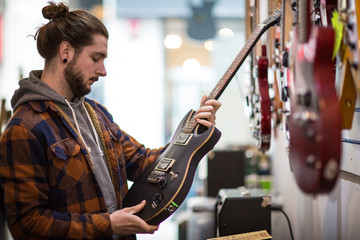 Young adult male looking at guitar in shop