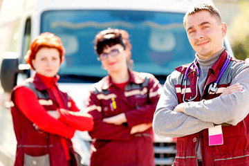 Smiling doctor man with paramedics coworker colleague on ambulance vehicle background