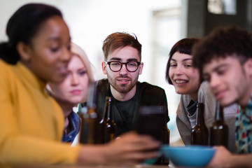 Group of friends looking at a smartphone together in a pub