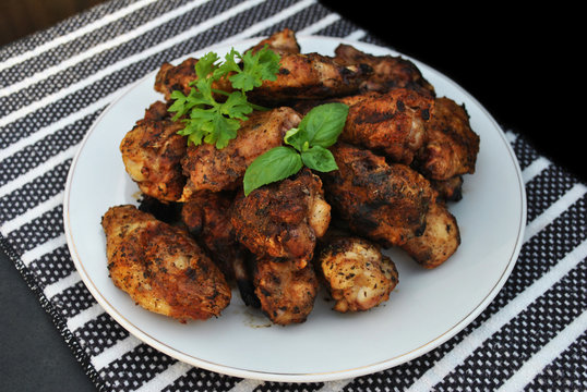 Plate of Grilled Chicken Wing Pieces Garnished with Parsley and Basil