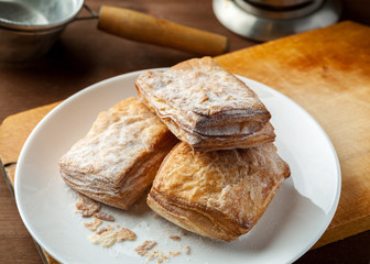 Puff pastries stacked in a white plate on a wooden table