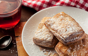 Puff pastries with cup of red fruit tea on a wooden table, selective focus, closeup shot