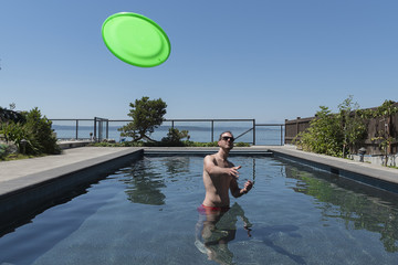 Man in swimming pool playing frisbee
