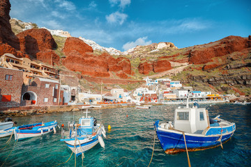 Fishing boats over turquoise color water moored at old port Amoudi of Oia village on Santorini...