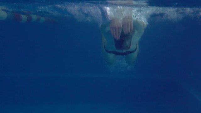 Beautiful Professional Swimmer Doing Butterfly Stroke In Pool With Rich Blue Water, Shot From Underwater