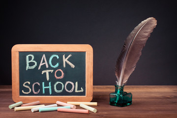 Vintage quill pen and Back to School written on a blackboard