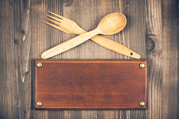 Sign board, fork and spoon on old wooden background