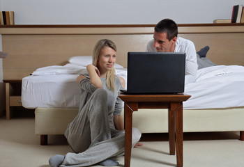 Online shopping, couple using electronic devices, laptop computer, modern cozy home interior