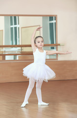 Fototapeta premium Beautiful little girl practicing ballet at class