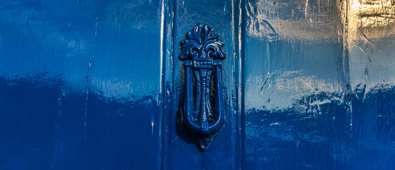 Blue door with brass knocker in decorative shape, beautiful home entrance, vintage decor
