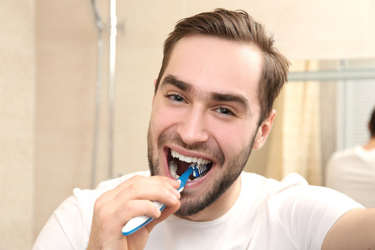 Handsome man brushing teeth in bathroom