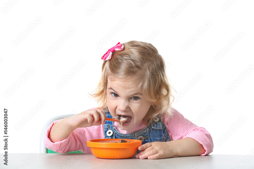 Poster Cute little girl eating yogurt with cornflakes on white background