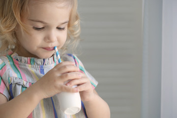 Cute little girl drinking yogurt at home