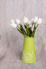 Tulipanes blancos en jarra sobre fondo de madera.
