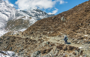 Porter walk on a trail in the valley Chhukung against peak Ama Dablam (6814 m) from the valley of...