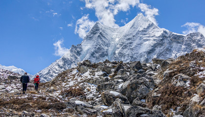 Tourists walk on a trail in the valley Chhukung against peak Ama Dablam (6814 m) from the valley of...