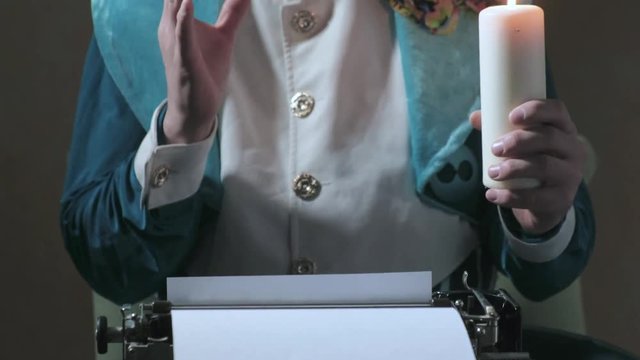 An illusionist writes on a typewriter holding a candle 4k