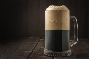 Dark beer mug with foam on dark background