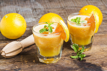 Fresh orange juice, mint and ice on dark background, top view