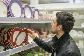 male customer choosing crockery plates in the hypermarket