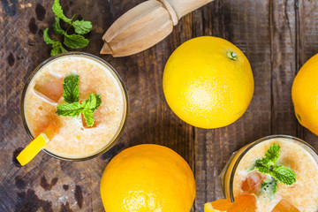 Fresh orange juice, mint and ice on dark background, top view