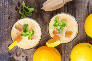 Fresh orange juice, mint and ice on dark background, top view