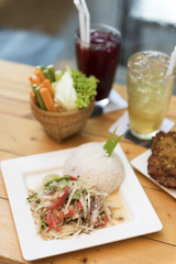 Thai style fish papaya salad with rice on table