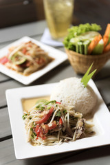 Thai style fish papaya salad with rice on table