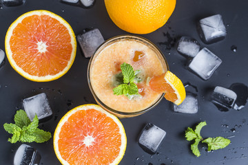 Fresh orange juice, mint and ice on dark background, top view