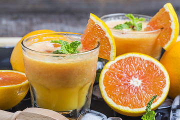 Fototapeta na wymiar Fresh orange juice, mint and ice on dark background, top view