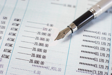 Fototapeta premium Pen with Finances statement ,hand pointing business charts,coins on paper work in the office,discussing stock marketing document,book bank