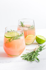 sliced lime, rosemary and natural juice in glass on white table background