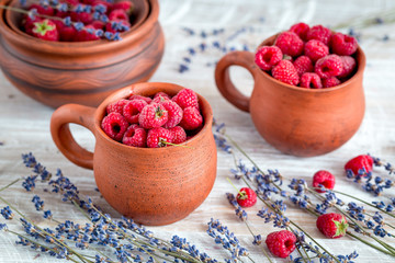 raspberry in pottery and lavender flowers on rustic background