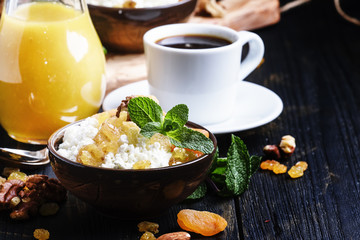 Breakfast with homemade cottage cheese, freshly squeezed juice, nuts and dried fruits, dark background, selective focus