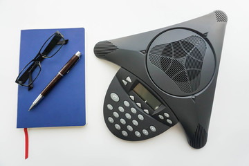 isolated voip IP conference phone with notebook and eyeglasses for taking minute of meeting in office